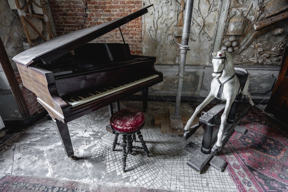 A vintage black grand piano with an open lid revealing the interior, positioned inside a room with weathered brick and ornate, aged wall decorations. In front of the piano is a small, round, padded st
